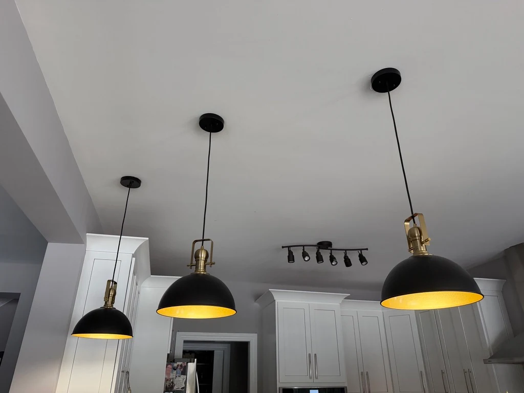 Angled view of three illuminated kitchen pendants with warm gold interiors