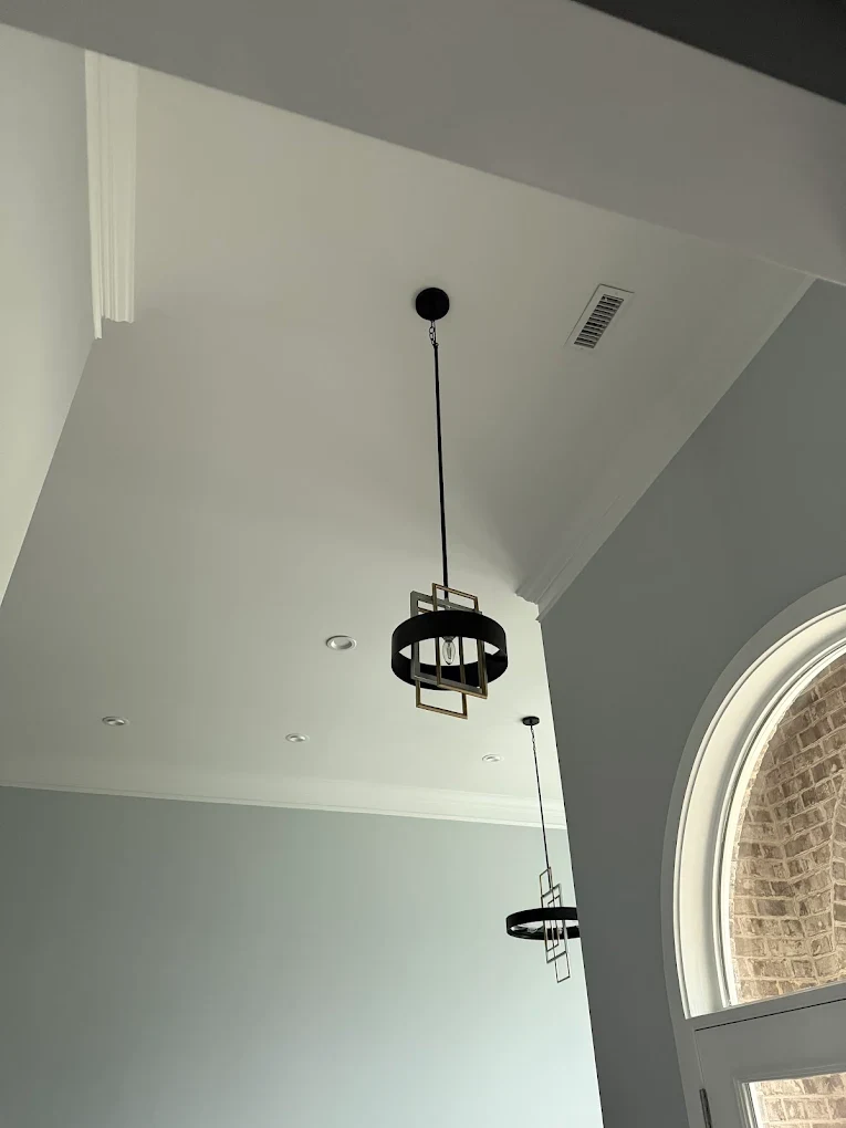 Two pendant light fixtures suspended in a tall entryway.